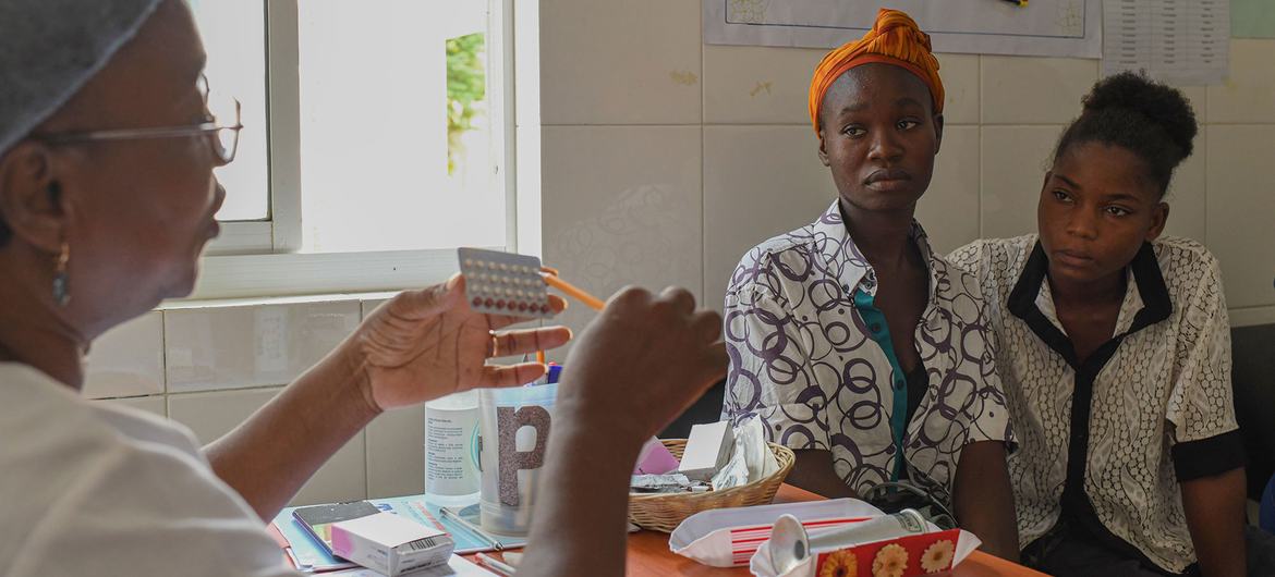 A nurse at the Family Planning Room in Centro de Saúde do Ramiro, Luanda, Angola, explains contraceptive options to two young women.