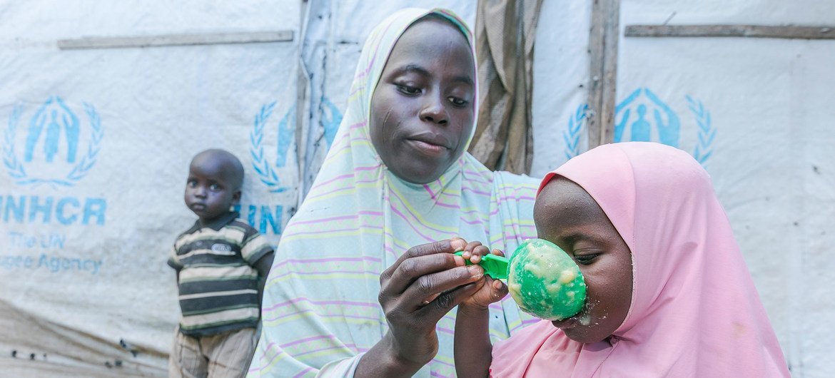 A mother prepares food for her children with cereal she received from a World Food Programme (WFP) distribution site in Maiduguri, Nigeria.