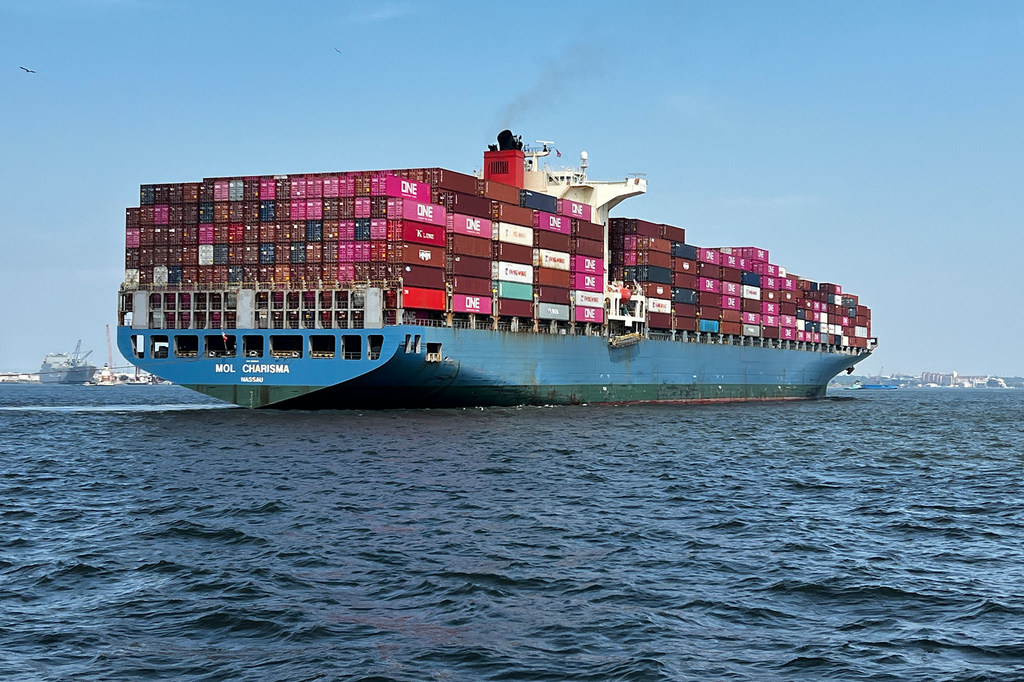 A large container ship named MOL CHARISMA sails on the open sea, loaded with colorful shipping containers.