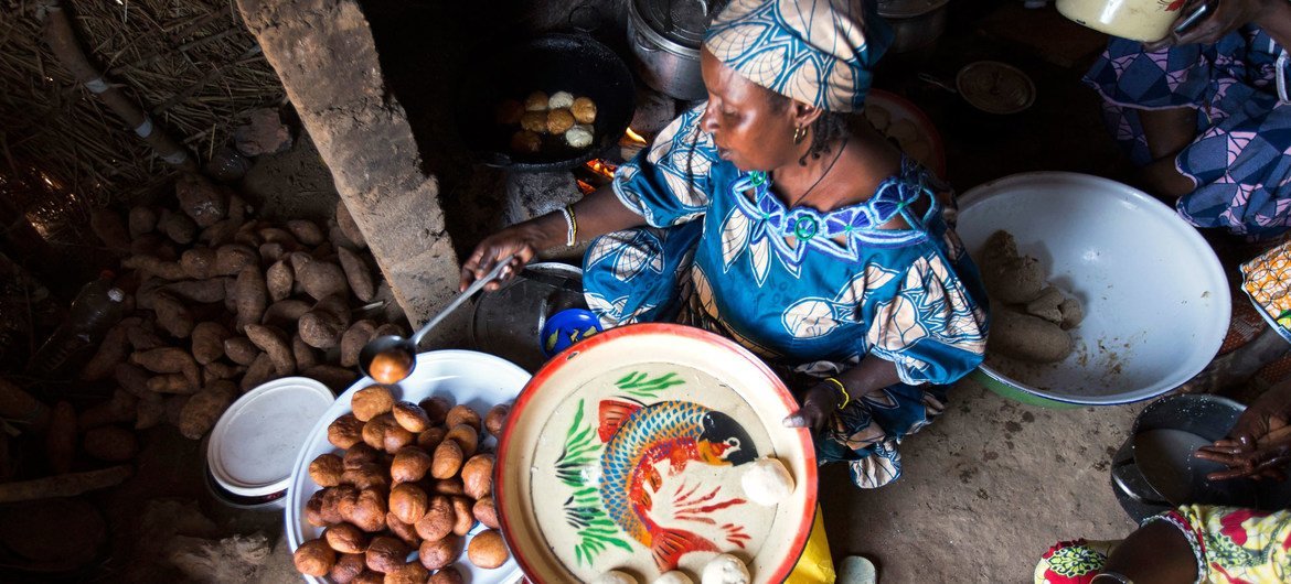 Kamerun'da yaşayan bir Orta Afrika Cumhuriyeti mültecisi müşterileri için yemek hazırlıyor. 