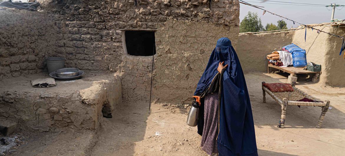 A woman in a blue burqa stands in the courtyard of a mud-brick house in Surkh Rod, Jalalabad, Afghanistan. The community received winter relief items.