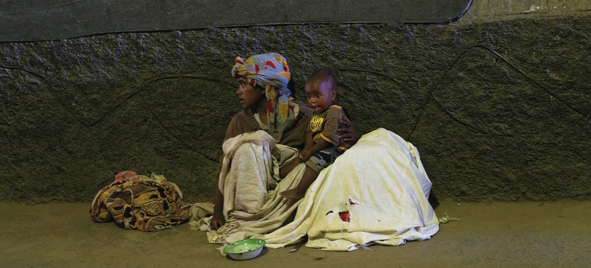 A woman and child sit on the ground in an urban setting in Antananarivo, Madagascar.