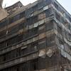 A multi-story concrete building in Iran with a weathered facade, featuring numerous windows and some scaffolding.