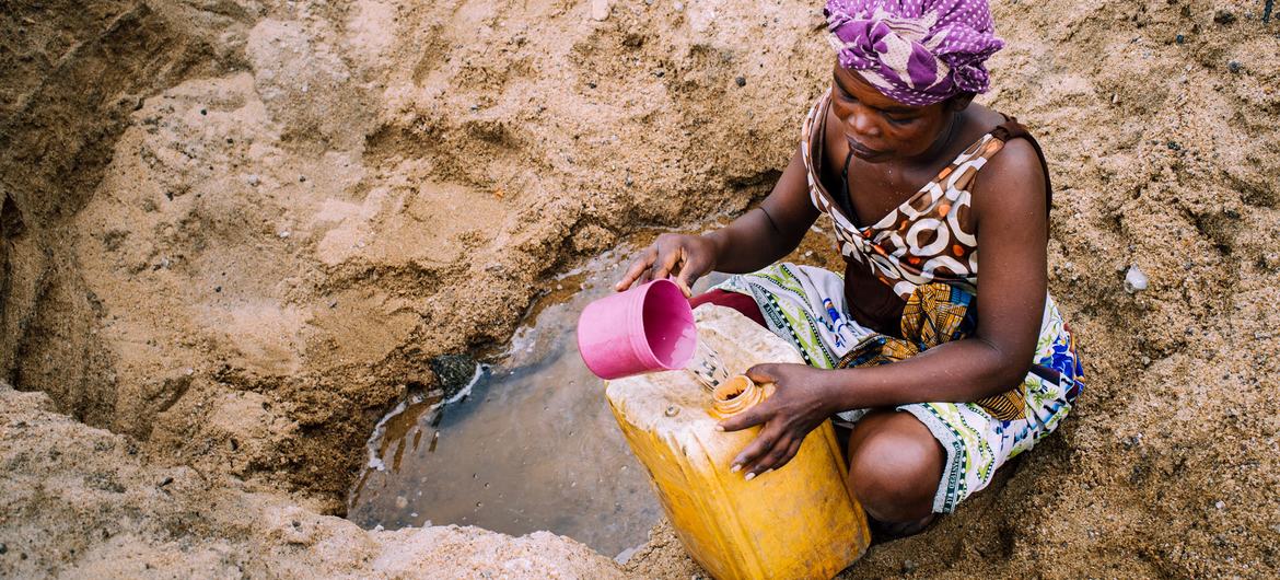 A woman collects water from a dry river bed during high water in Madagascar.