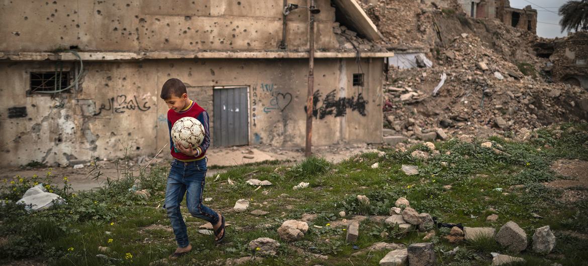 A boy carries a football ball in the Old City of Mosul in Iraq. A boy carries a football ball in the Old City of Mosul in Iraq.