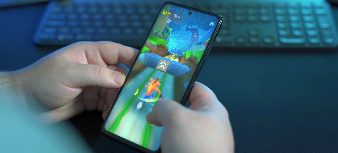 A young man plays famous mobile game Crash Bandicoot on his smartphone.