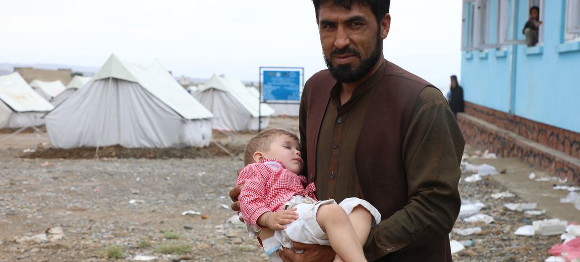Bir baba, evinin son selde yıkıldığı Afganistan'ın Logar Eyaletinde tedavi görmek için UNICEF tarafından desteklenen bir gezici sağlık kliniğine çocuğunu getiriyor.