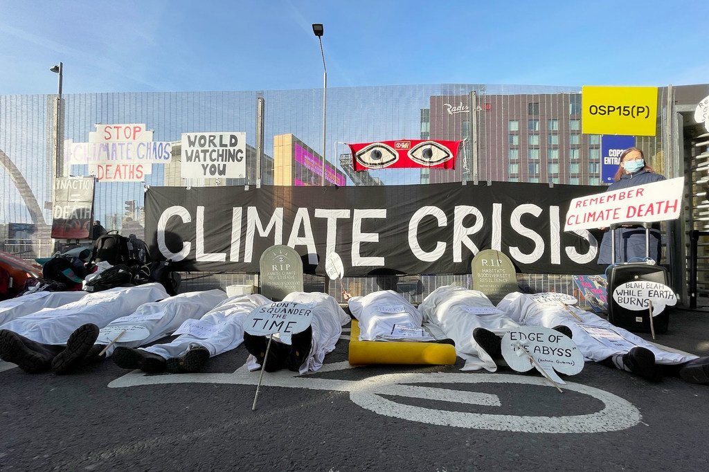 Protesters demonstrate outside COP26 in Glasgow, using symbolic tombstones and white sheets to represent victims of the climate crisis.