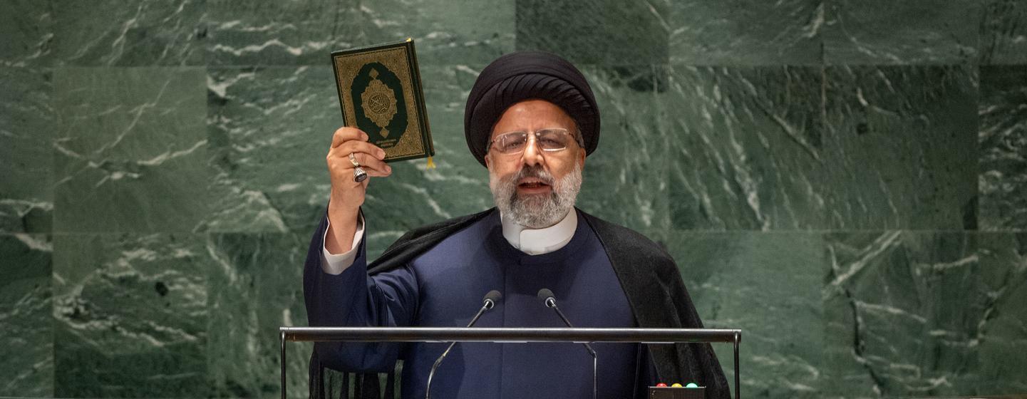 Iranian President Seyyed Ebrahim Raisi holds up a book while speaking at a podium with the UN emblem, during a General Assembly session in New York.