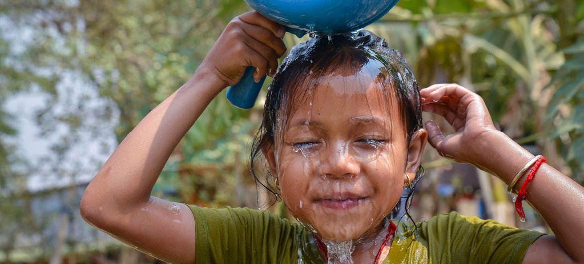 A young girl washes her face using newly installed piped water at her home in Cambodia.