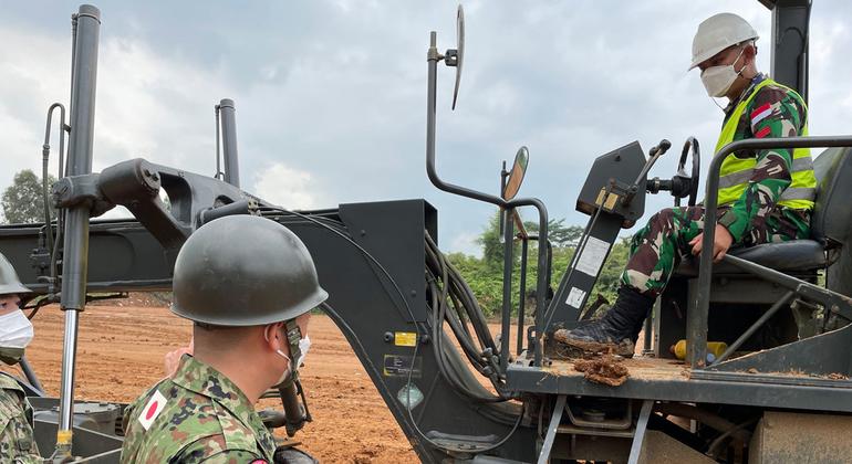 A Japanese military instructor helps a soldier from the Indonesian army's 3rd Combat Engineer Battalion hone his skills in driving a grader, equipment he will need to operate the MINUSCA peacekeeping mission in Central African Republic.