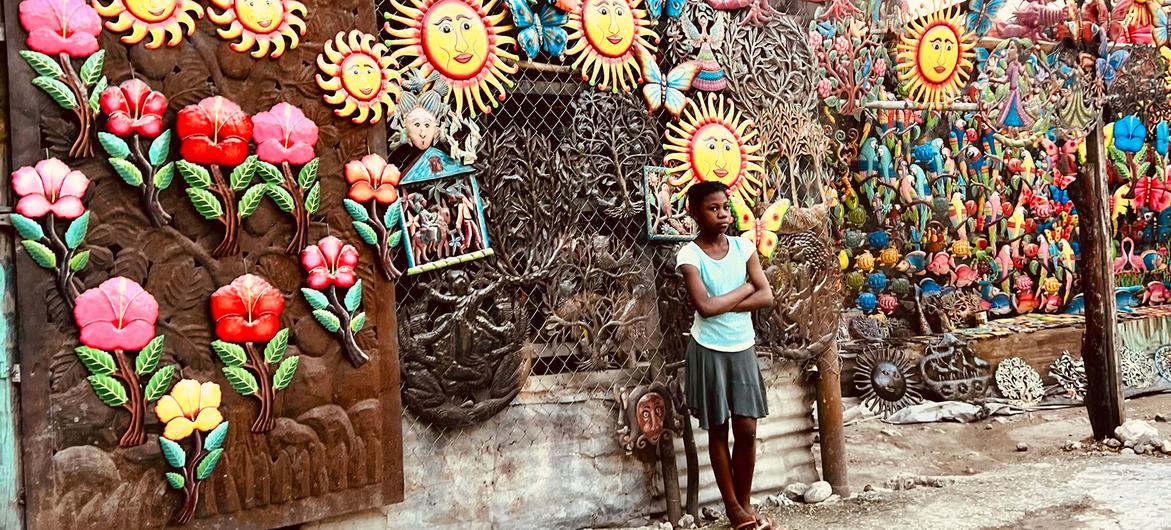 A young woman displays souvenir items for sale on a wall in a Port-au-Prince neighbourhood.