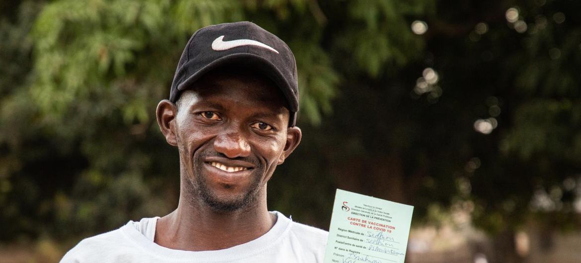 A Senegalese man holds up his COVID-19 vaccination card