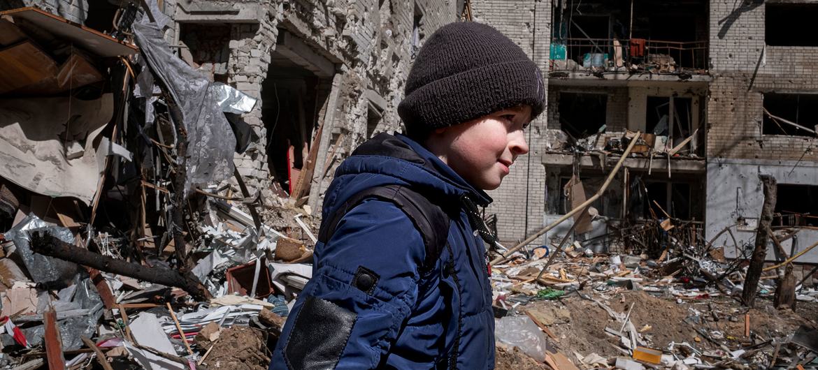 Ukrayna'nın Chernihiv kentindeki bir hava saldırısında yıkılan ailesinin evinin önündeki avluda on yaşında bir çocuk yürüyor.