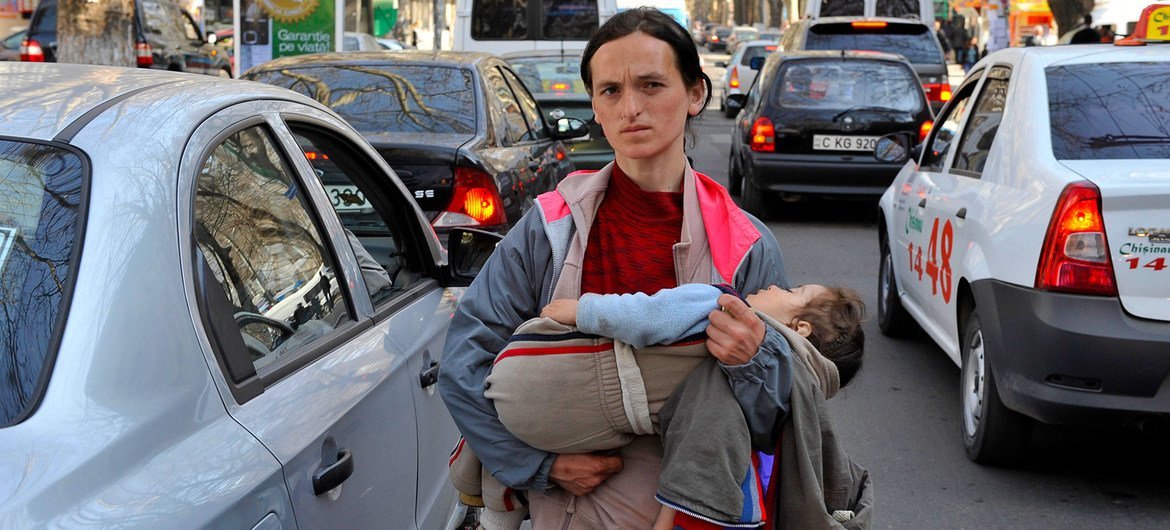 A woman carries her child while begging on the streets of Chisinau in Moldova. A woman carries her child while begging on the streets of Chisinau in Moldova.