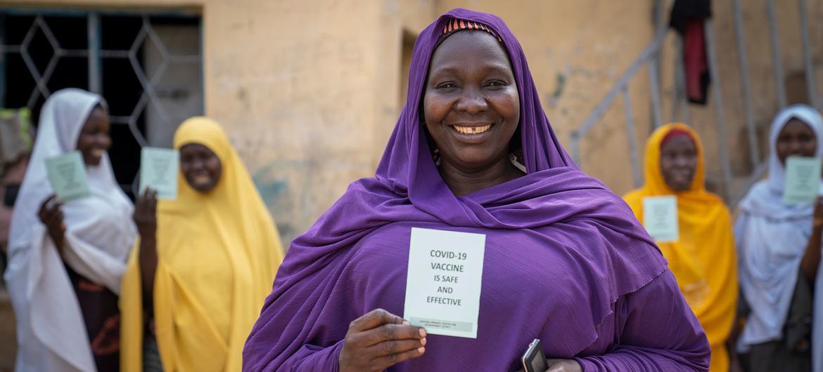 A woman shows her COVID-19 vaccine card alongside her sisters in Kano, Nigeria. A woman shows her COVID-19 vaccine card alongside her sisters in Kano, Nigeria.