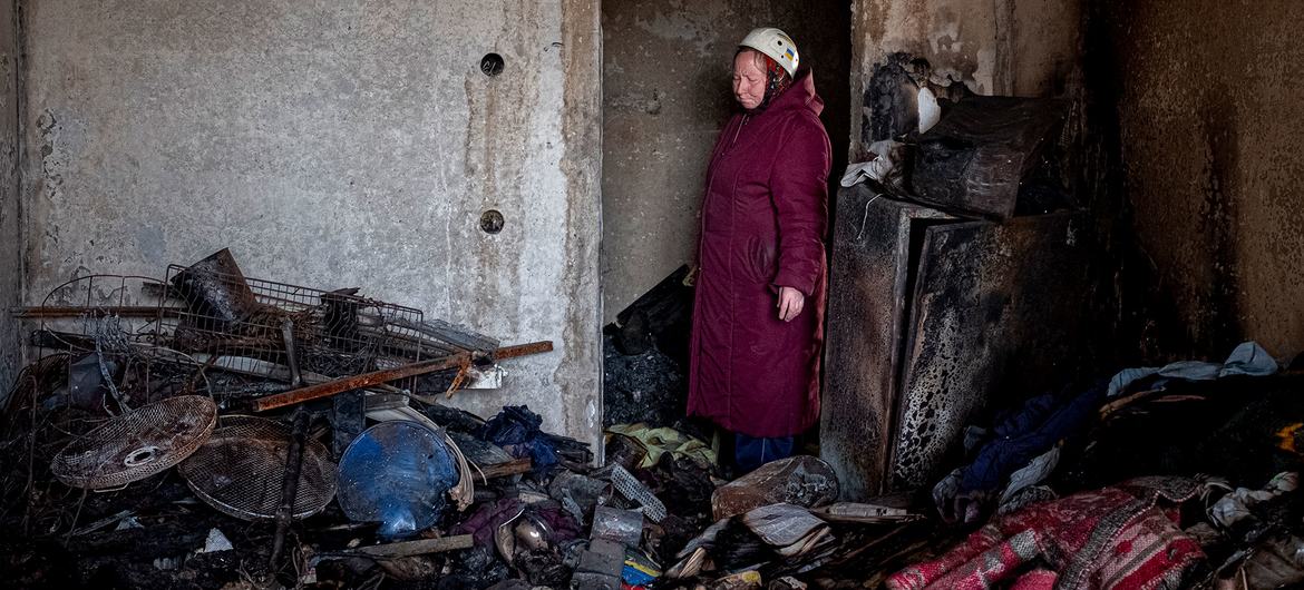 70 yaşında bir kadın, Ukrayna'nın Chernihiv kentinde bombalanan ve yanmış dairesinin kapısında duruyor.
