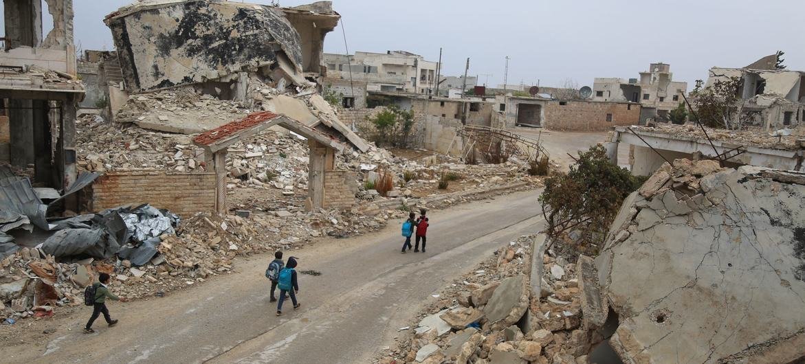 Children walk past ruins on their way home from school in Syria. Children walk past ruins on their way home from school in Syria.