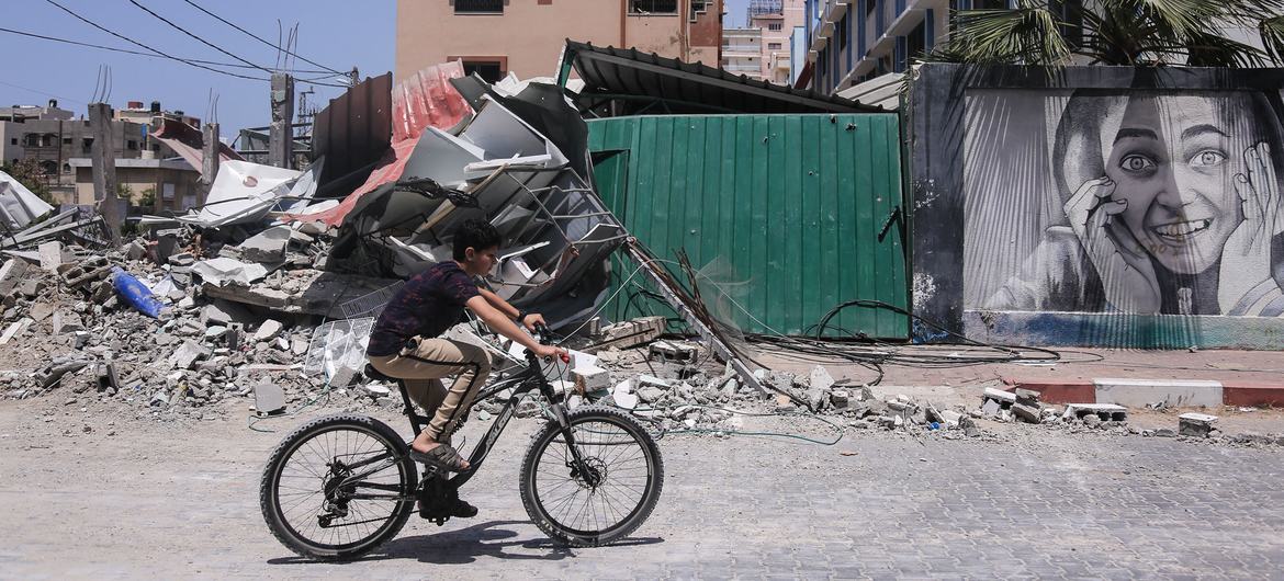 Filistin'in Gazze Şeridi'nde İsrail saldırılarının ardından yıkılan binaların yanında bisiklet süren bir çocuk.