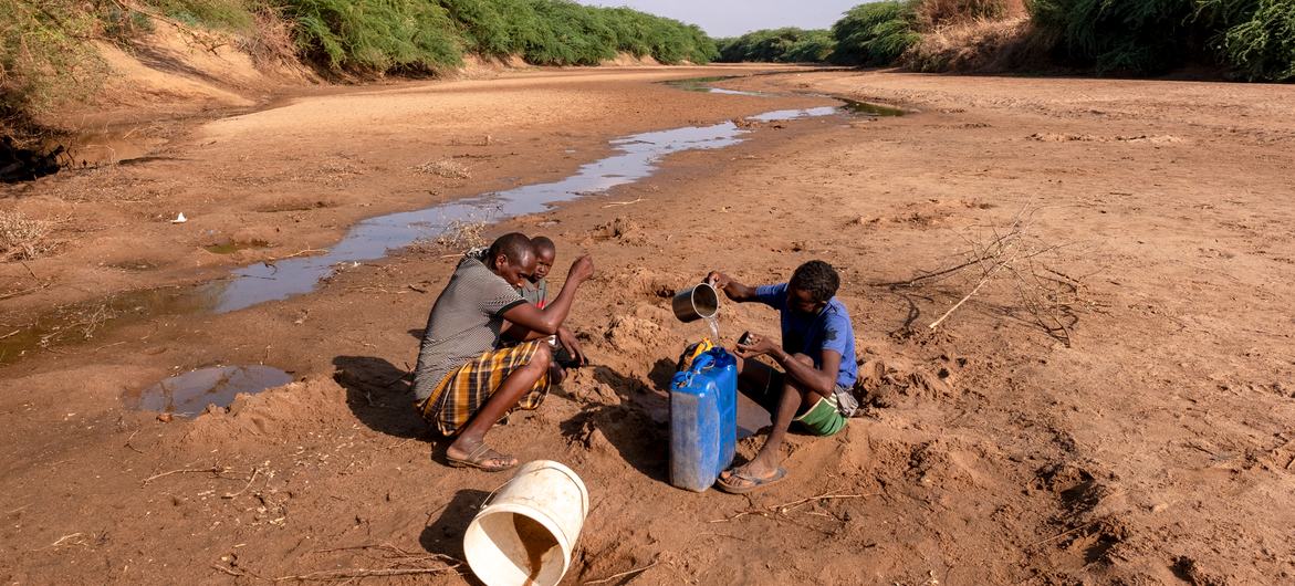 A man with his children collecting  water from the dried up  Dollow River, Somalia.