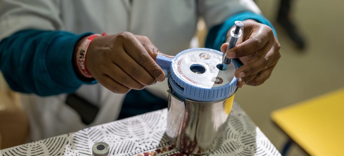 A medical worker discards a used COVID vaccine syringe into a container. A medical worker discards a used COVID vaccine syringe into a container.