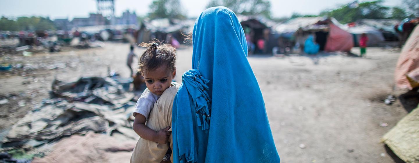 A mohter holds her child in the slum where they live in Vijaynagar, India. A mohter holds her child in the slum where they live in Vijaynagar, India.