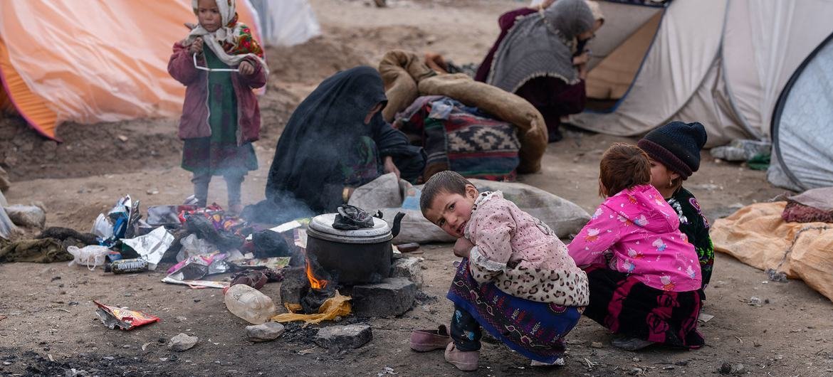 Children use the heat from a firewood stove to keep themselves warm in the hard Afghan winter. Children use the heat from a firewood stove to keep themselves warm in the hard Afghan winter.