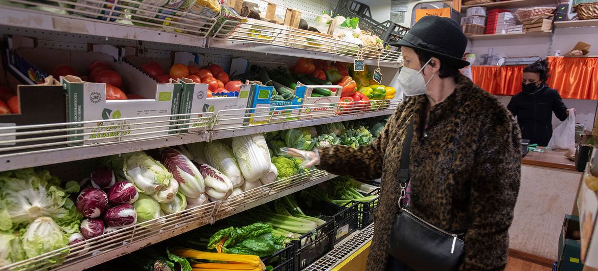 A woman buys fresh vegetables at an organic farm store in Rome, Italy.