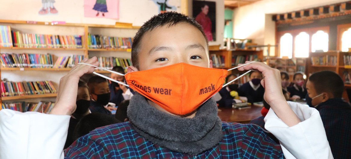 A grade six student of Drugyel Lower Secondary School in Paro, Bhutan, shows the message on his mask: Heroes wear mask.