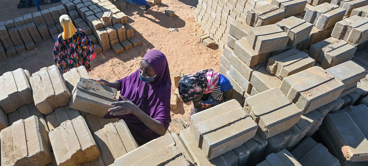 A woman stacks new bricks in Ouallam brickyard, in camp for displaced peoplle and refugees in Niger. A woman stacks new bricks in Ouallam brickyard, in camp for displaced peoplle and refugees in Niger.