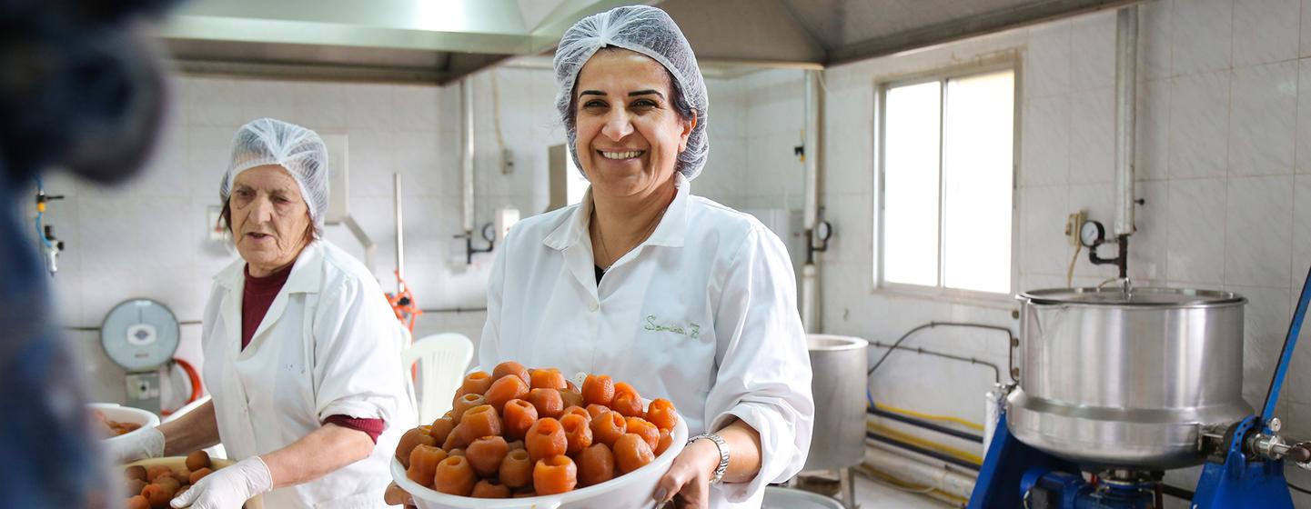 Samira Zoughaib Akiki, Chair of Al Atayeb Cooperative, holding a basket of fresh apple marmalade. Samira Zoughaib Akiki, Chair of Al Atayeb Cooperative, holding a basket of fresh apple marmalade.