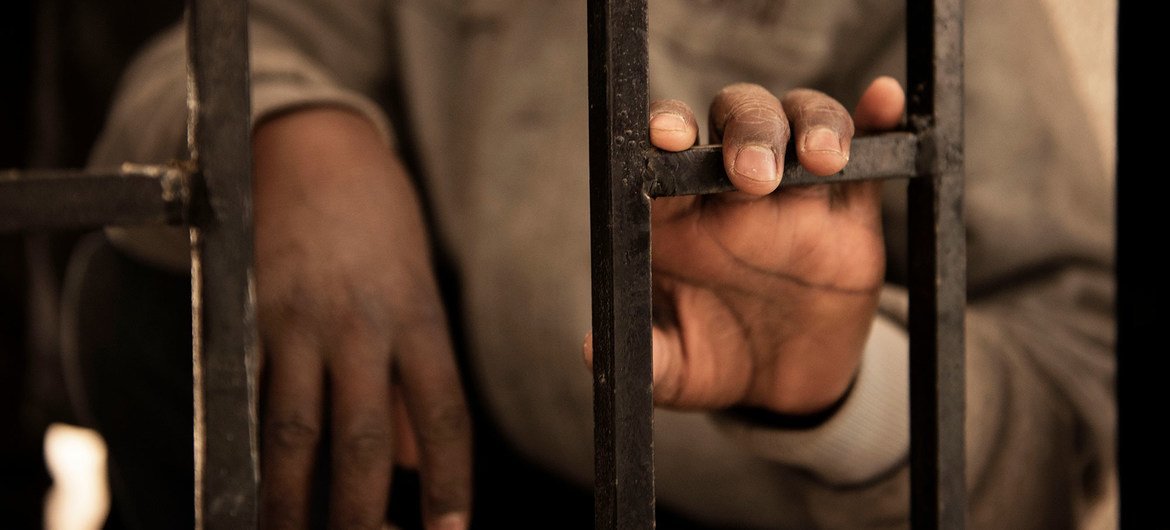 A fourteen-year-old migrant from Niger rests his hand on a gate inside a detention centre, in Libya. A fourteen-year-old migrant from Niger rests his hand on a gate inside a detention centre, in Libya.