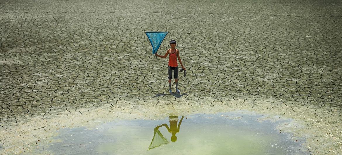 A young boy stands in front of a waterhole in a drought zone in Bangladesh. A young boy stands in front of a waterhole in a drought zone in Bangladesh.