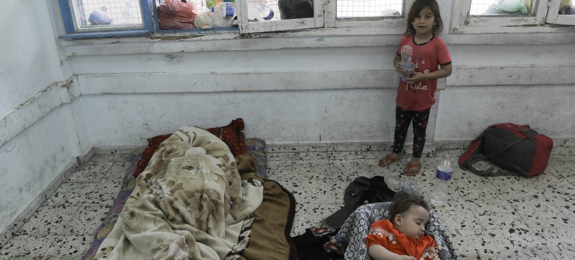 A child cares for her sleeping baby siblings in a classroom at the UNRWA Salah Eddin School in Gaza.
