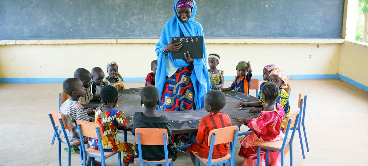 Children sit in a circle with their teacher at the Early Childhood Development center in Garin Badjini village, southeastern Nigeria.