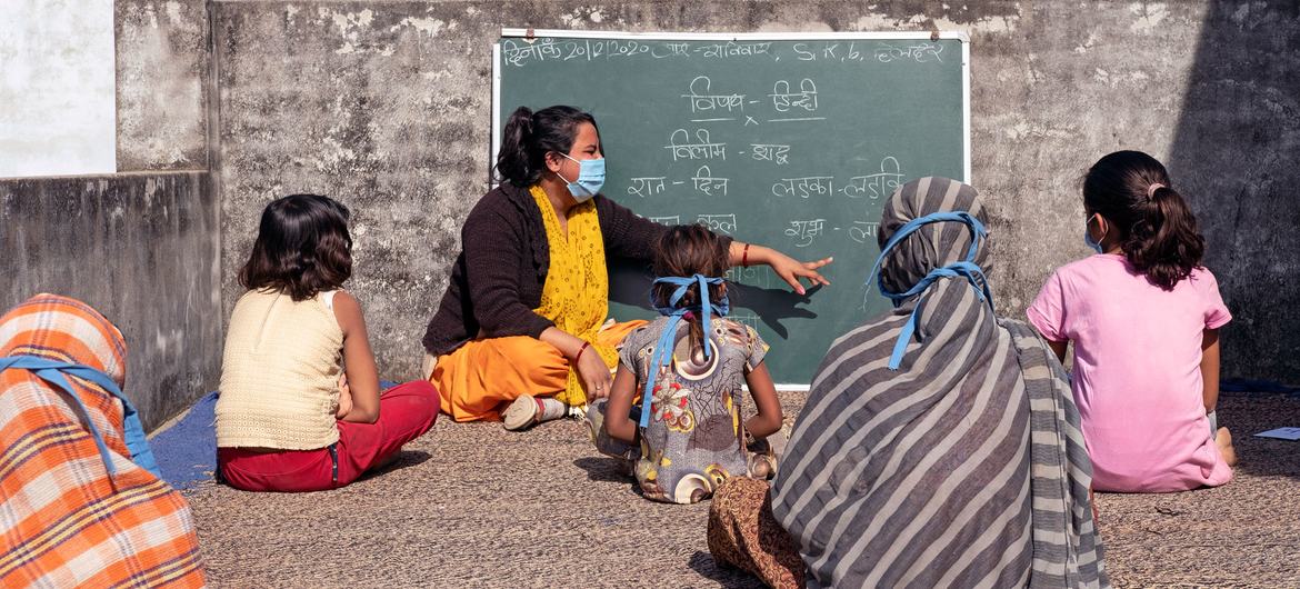 Children practice social distancing during class in India. Children practice social distancing during class in India.