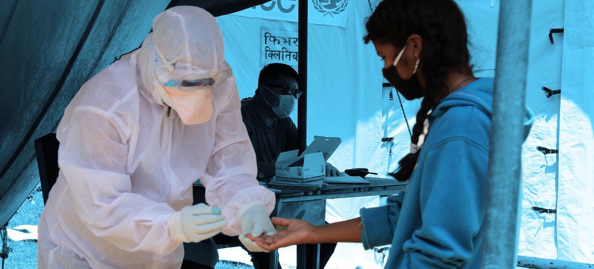 A health worker screens a young girl for COVID-19 at a fever clinic set up next to a hospital in Saptari District , Nepal. A health worker screens a young girl for COVID-19 at a fever clinic set up next to a hospital in Saptari District , Nepal.