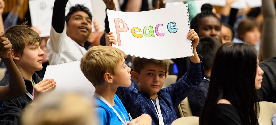 Evrensel Çocuk Günü münasebetiyle düzenlenen özel bir etkinlikte, dünyanın dört bir yanından gençler barış çağrısı yapan pankartlar taşıyor.