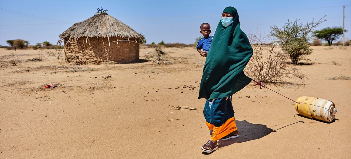Kenya'nın Garissa ilçesinde bir kadın iki yaşındaki oğluyla birlikte bir su büfesine yürüyor.