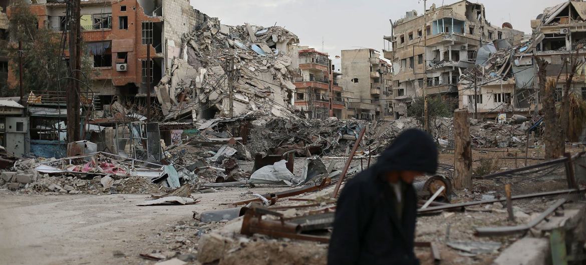 A man walks in front of destroyed buildings in Harasta, Syria. A man walks in front of destroyed buildings in Harasta, Syria.