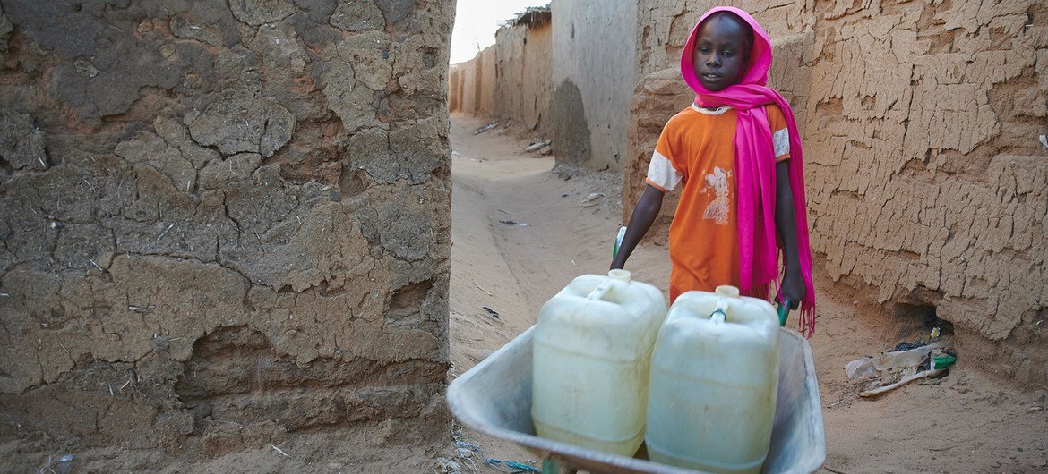 A nine-year-old girl pushes a wheelbarrow loaded with water-filled jerrycans in a IDP camp in Darfur, Sudan. A nine-year-old girl pushes a wheelbarrow loaded with water-filled jerrycans in a IDP camp in Darfur, Sudan.