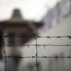 Barbed wire fence in the foreground with a blurred building in the background