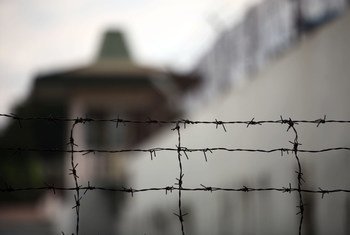 Barbed wire fence in the foreground with a blurred building in the background
