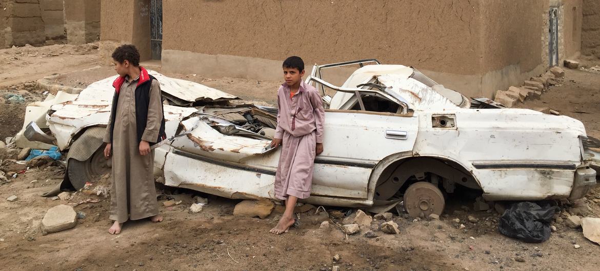 Yemen'in Sa'ada kentinde genç çocuklar hasarlı bir aracın önünde duruyor.