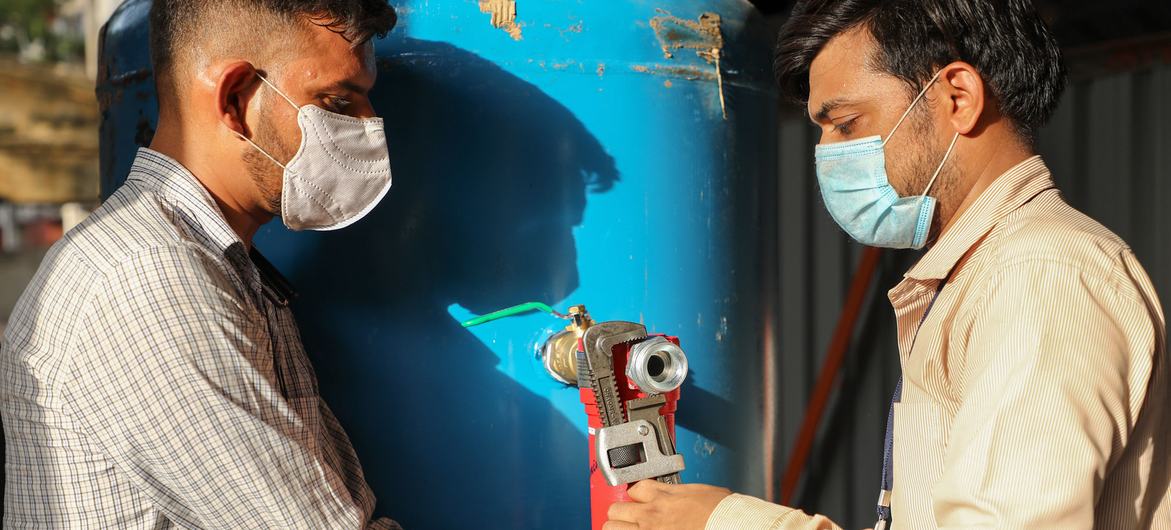 Two workers set up the oxygen cylinders for treating patients with respiratory diseases, in India. Two workers set up the oxygen cylinders for treating patients with respiratory diseases, in India.