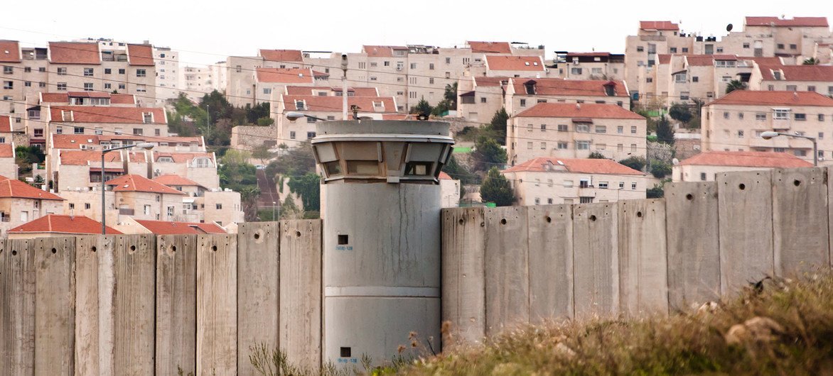 The Separation Wall in the occupied Palestinian Territory and behind it an Israeli settlements. The Separation Wall in the occupied Palestinian Territory and behind it an Israeli settlements.
