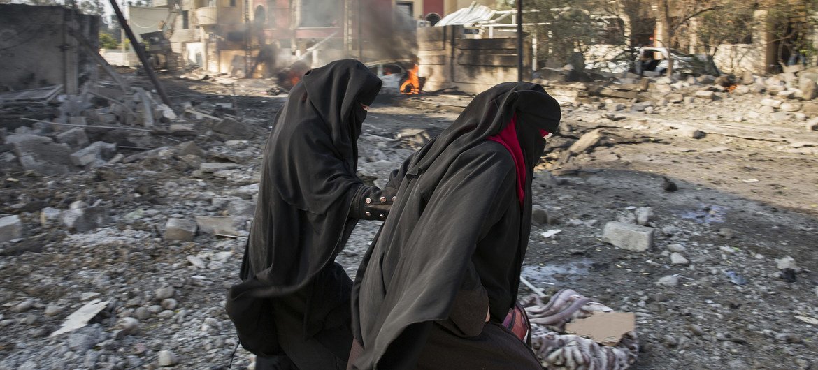 Civilians pass a burning automobile following a suicide car bombing.in Mosul, Iraq, Civilians pass a burning automobile following a suicide car bombing.in Mosul, Iraq,