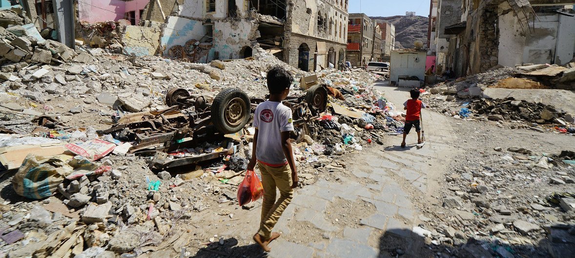 Çocuklar, Yemen'in Aden kentindeki Craiter şehir merkezinin hasarlı bir bölümünden geçiyor.  Bölge, 2015 yılında Husiler koalisyon güçleri tarafından şehirden sürüldüğü için hava saldırılarında ağır hasar gördü.